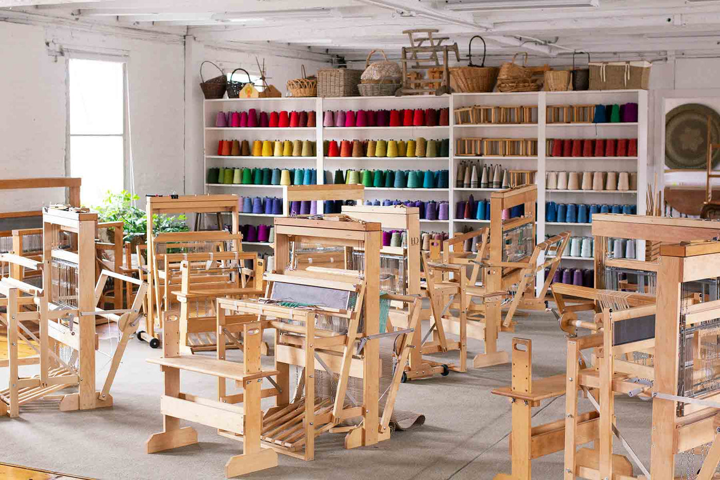 Weaving studio with a multicolored yarn wall and several floor looms