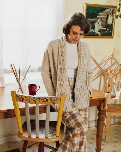 woman standing in pajamas with a knit oversized cream cardigan
